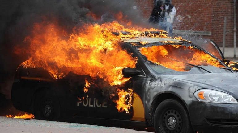 An officer vehicle burns Monday, April 27, 2015, during unrest...