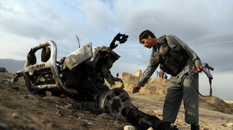 Afghan security forces check the bomb site Tuesday, a day...