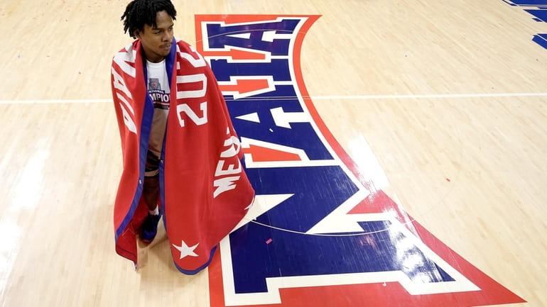 Freed-Hardeman guard Quan Lax wears the cmanpionship banner after the...
