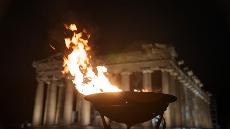 A cauldron with the Olympic flame burns in front of...