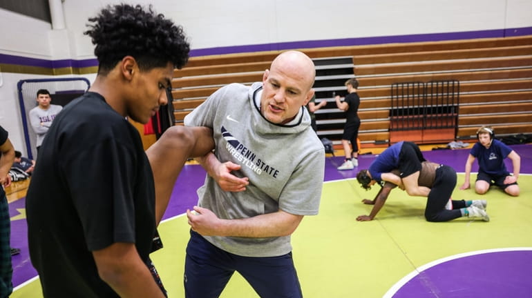 Penn State University wrestling coach Cael Sanderson, right, works with...