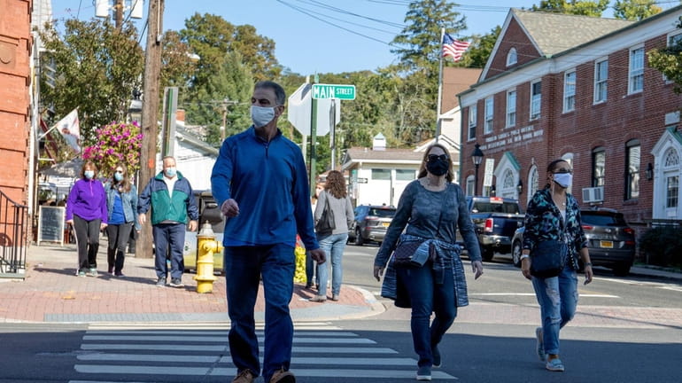 People walk while wearing masks in Port Jefferson in October. Nearly...