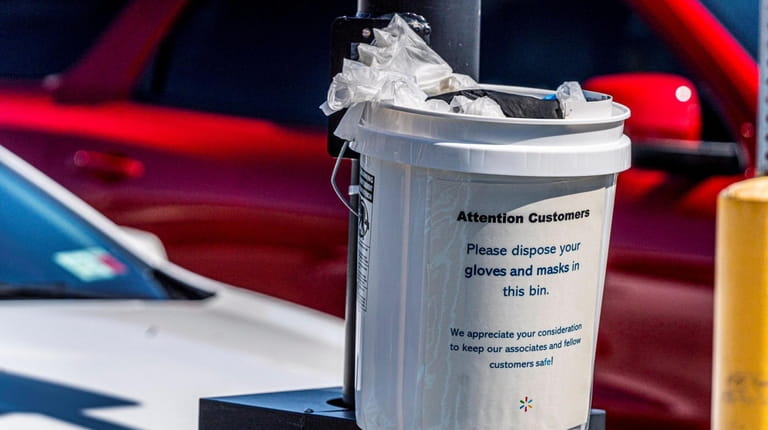 A pail to dispose gloves and masks is placed in...