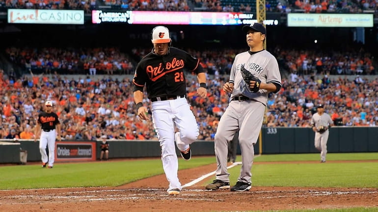 Steve Pearce of the Baltimore Orioles scores a run on...
