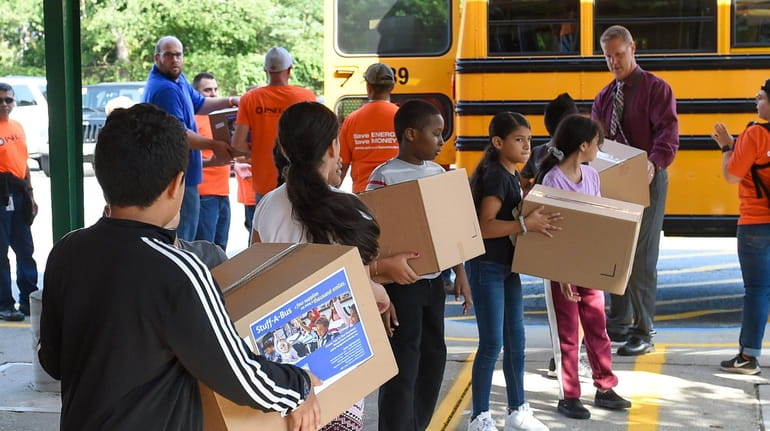 Students from Loretta Park Elementary School help unload "Stuff-A-Bus" school supplies...