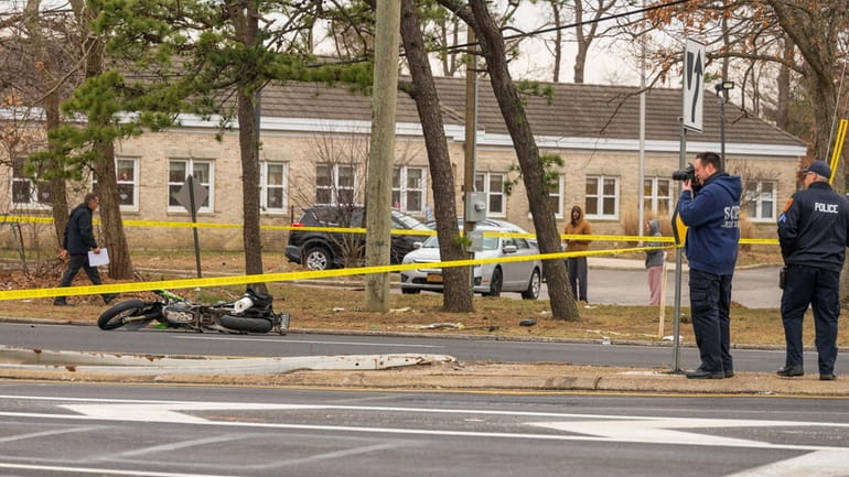 Suffolk County police investigate the scene where a motorcyclist was...