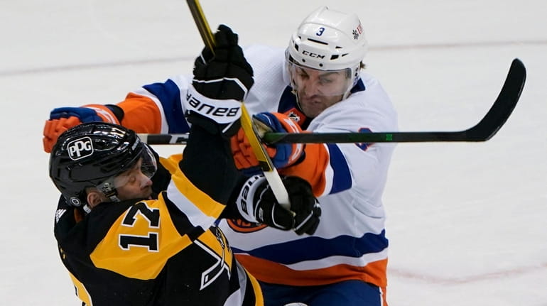 The Islanders' Adam Pelech checks the Penguins' Bryan Rust during the first...