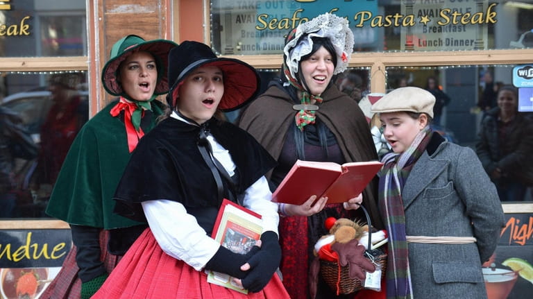 A group of holiday carolers serenade an audience on the...