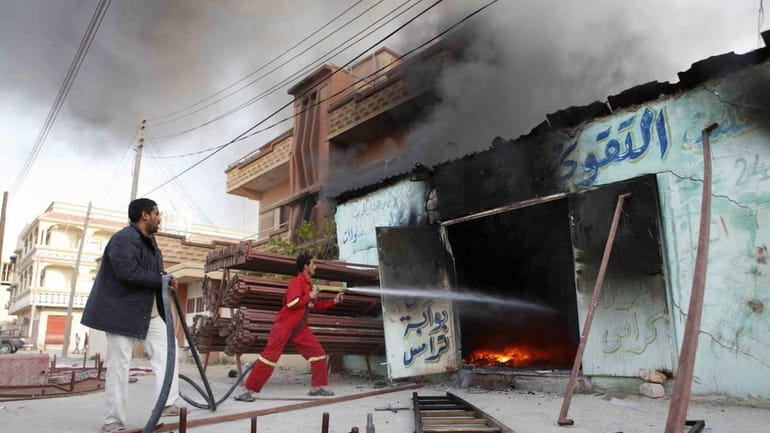 Libyan men fight a fire in the city of Ajdabiya,...