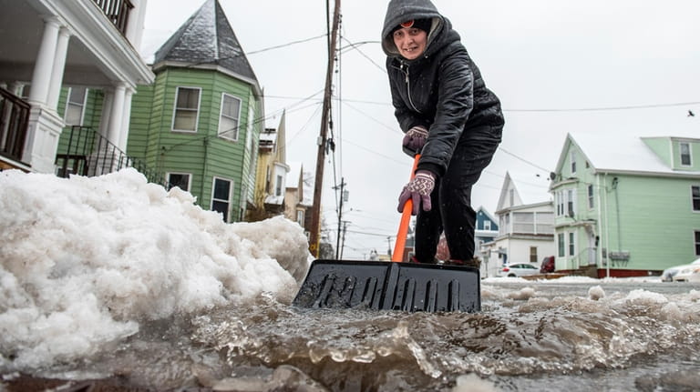 Amber Vallee pushes water down Walnut Street in Lewiston, Maine,...