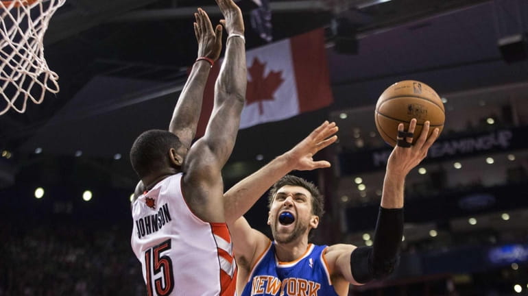 Knicks' Andrea Bargnani, right, shoots on Toronto Raptors' Amir Johnson...