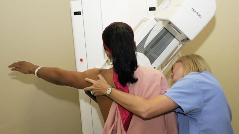 A Radiology technician prepares a woman for a mammography, a...