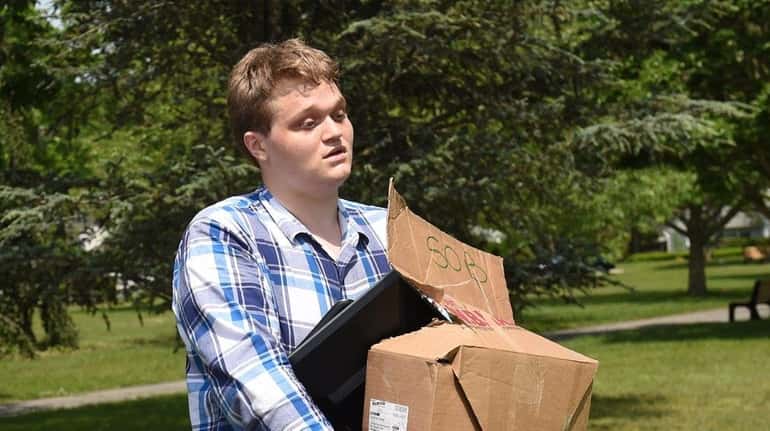 Chris Snyder, 22, of Shirley, carries his belongings as he...