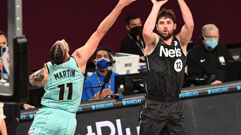 Nets forward Joe Harris shoots from outside defended by Charlotte...