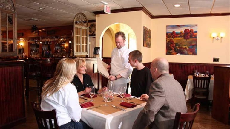The chef shows the restaurant's menu to patrons at Bistro...