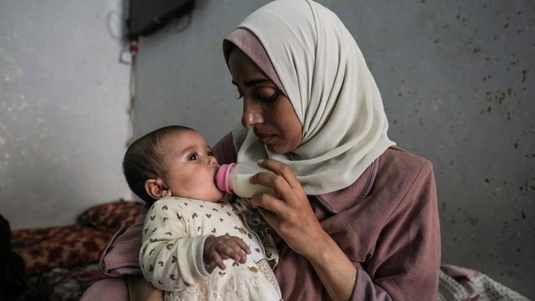Rola Saqer feeds her baby Massa Mohammad Zaqout in her...