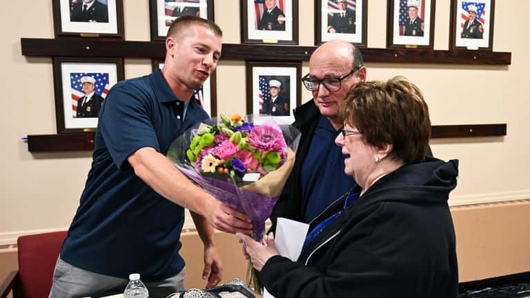 Commack Third Assistant Fire Chief Christopher Ciaccio presents flowers to Evelyn...