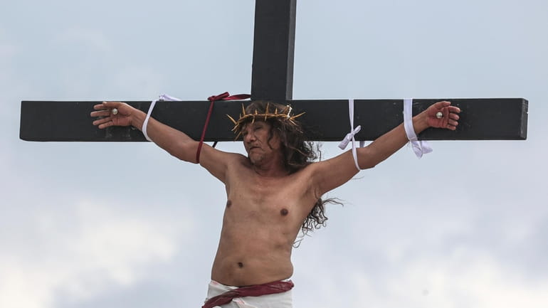 Ruben Enaje remains on the cross during the reenactment of...