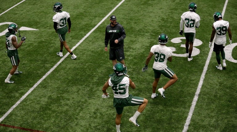 Jets head coach Adam Gase watches players stretch during an...