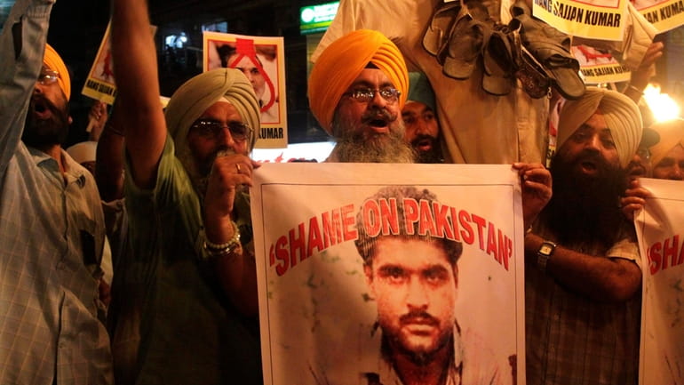Indian Sikhs shout slogans against Pakistan as they display photographs...