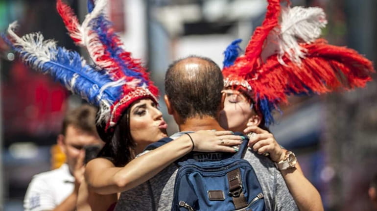 Topless women pose for pictures with tourists in Times Square...