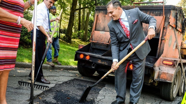 Oyster Bay Town Supervisor Joseph Saladino helps shovel asphalt after...