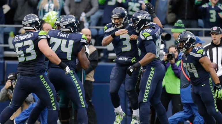 Seattle Seahawks quarterback Russell Wilson (3) is greeted by teammates...