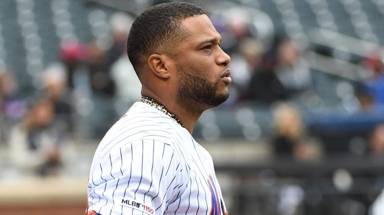 Mets second baseman Robinson Cano takes his left glove off...