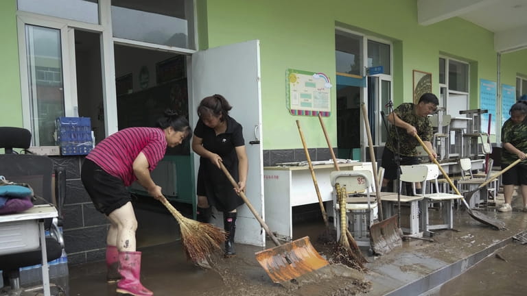 In this photo released by Xinhua News Agency, teachers clean...