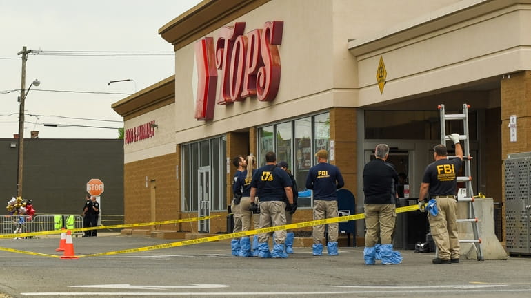 FBI agents gather evidence at the entrance of the Tops...