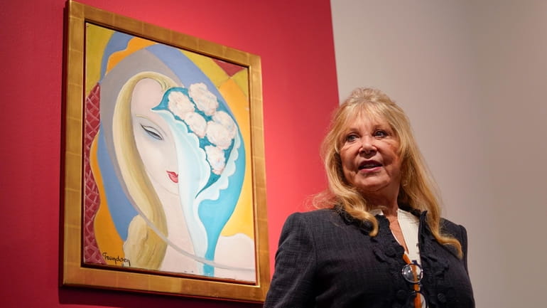 Pattie Boyd poses next to the original artwork by E....