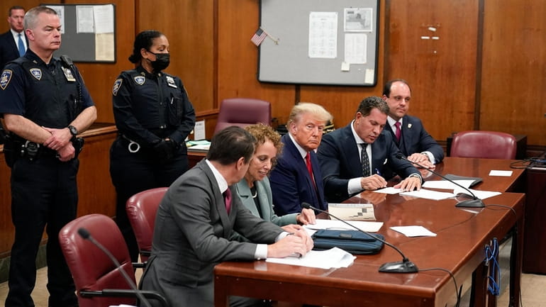 Former President Donald Trump, center, appears in court for his...