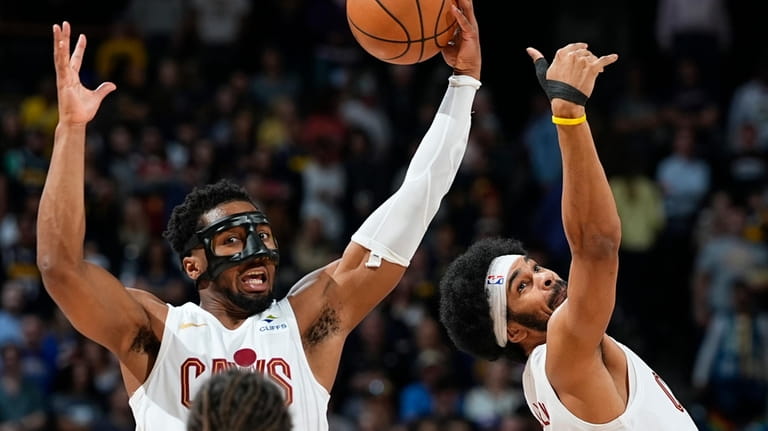 Cleveland Cavaliers guard Donovan Mitchell, back left, pulls in a...