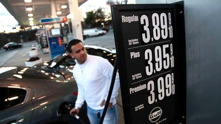 Tristan Robles, of Selden, pumps gas at a station in...