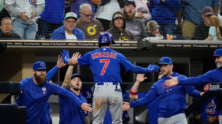 Chicago Cubs' Dansby Swanson (7) is greeted at the dugout...