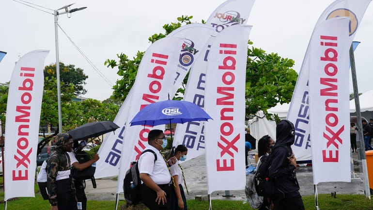 High school students walk past ExxonMobil flags as they arrive...