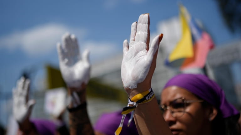 People with their hands painted white march on International Women's...