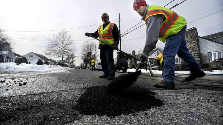 Town of Hempstead workers Ron Peterson and Javier Peralta fill...