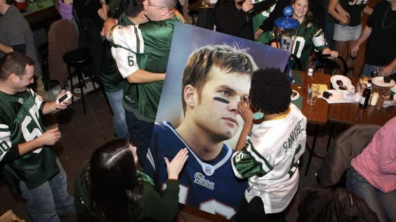 Jets fans pass around a poster-sized photo of Patriots quarterback...