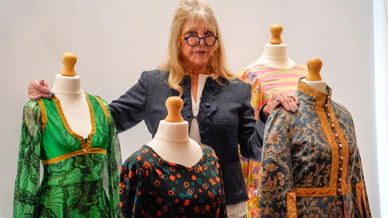 Pattie Boyd poses next to dresses from The Pattie Boyd...