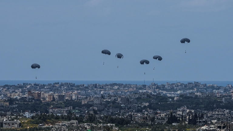 Parachutes drop supplies into the northern Gaza Strip, as seen...