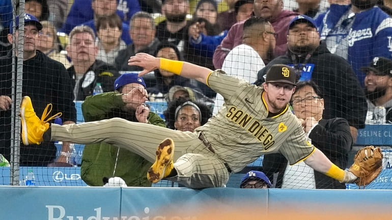 San Diego Padres' Jake Cronenworth falls against the netting after...