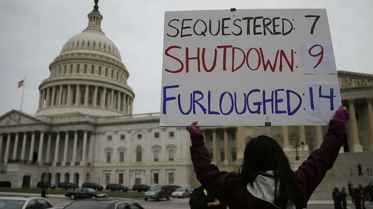 A woman holds a sign about the federal government shutdown...