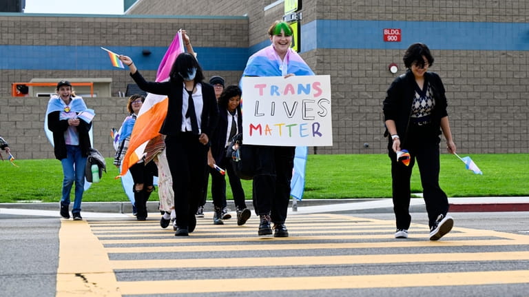 Students carrying pride flags and transgender flags leave Great Oak...