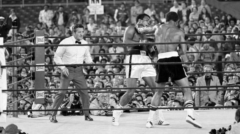 Muhammad Ali, center, tries to avoid a left hand punch...