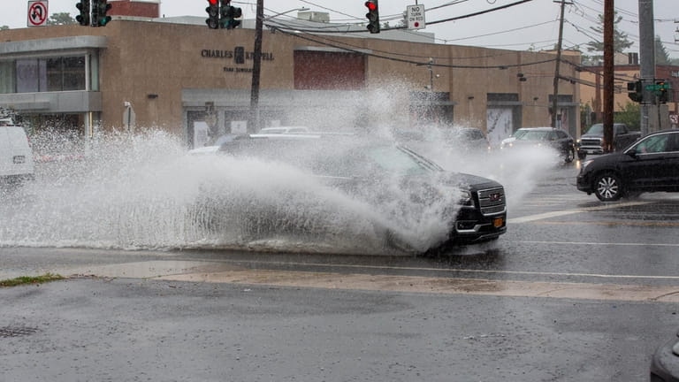 Cars and trucks splash though the puddles left by a...
