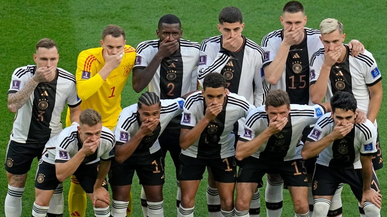 Germany's soccer team players cover their mouths as they pose...