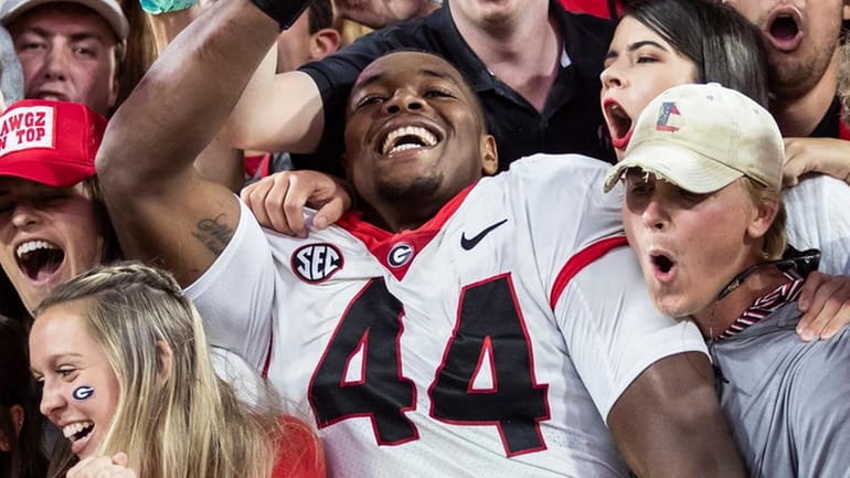 Travon Walker of the Georgia Bulldogs celebrates with fans after defeating...