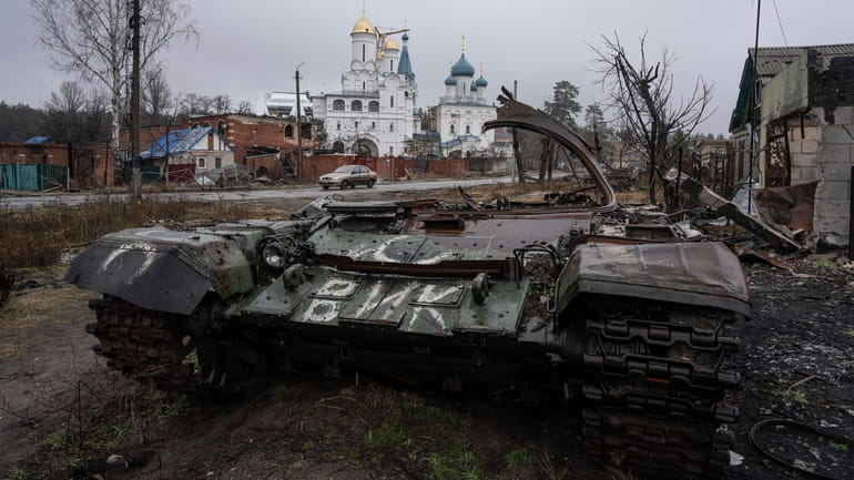 A destroyed Russian tank stands across the road of a...