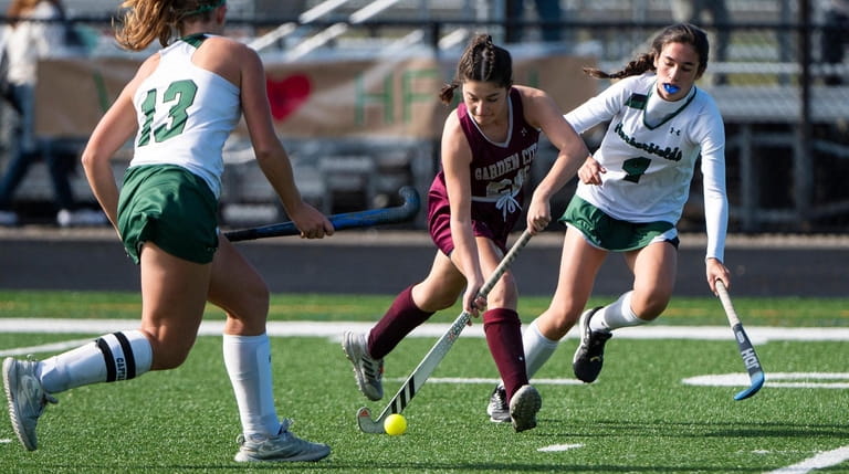 Garden City's Blakely Trapani moves between two Harborfields defenders in the Long Island...